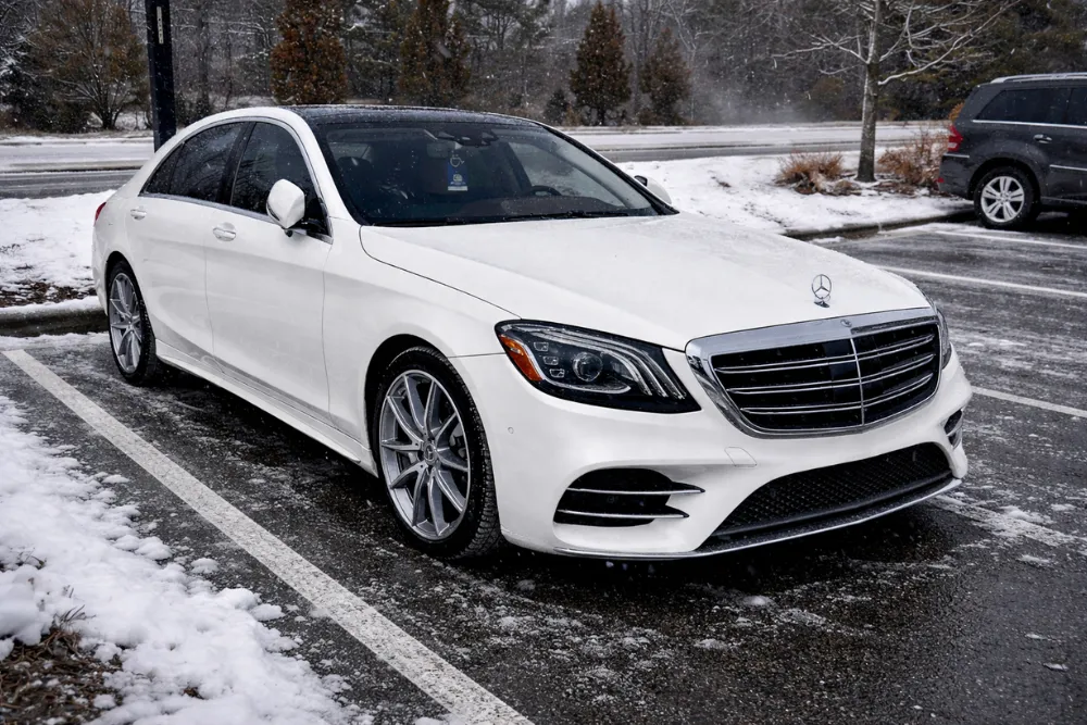 Suspension repair, auto repair in Apex, NC by CW Performance. Image of a white Mercedes-Benz sedan parked on a snowy lot. Highlighting precision service, winter driving reliability, and peak European vehicle performance.