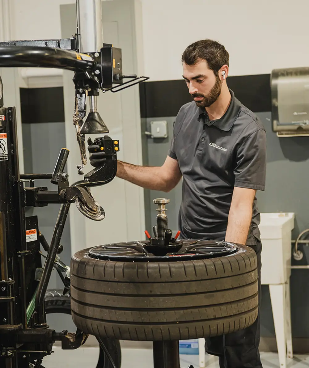 Mechanic working on tire and wheel alignment machine at CW Performance in Apex, NC
