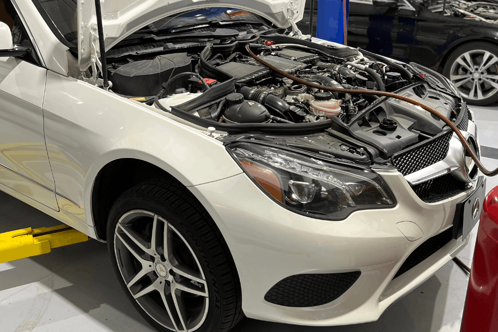 Mercedes-Benz engine repair in Apex, NC at CW Performance. Image of a white Mercedes with the hood open and service equipment connected in the engine bay for inspection and maintenance.